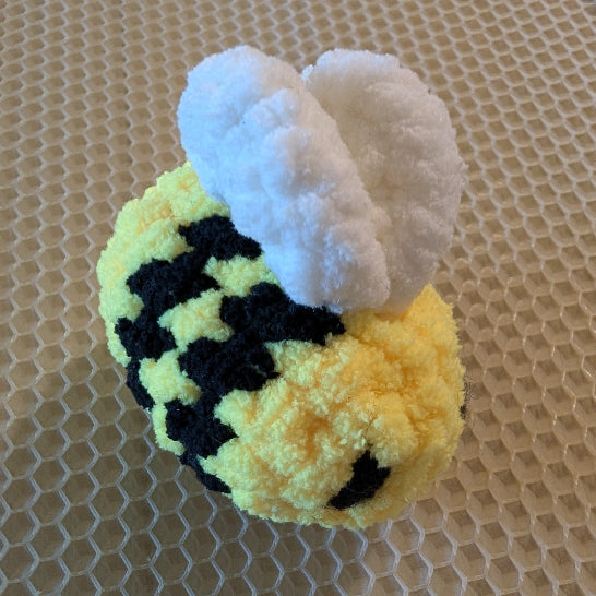 Small plush bee toy on a textured surface
