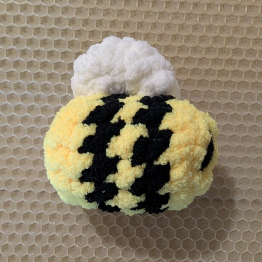 Fuzzy bee-shaped toy on a textured beige background